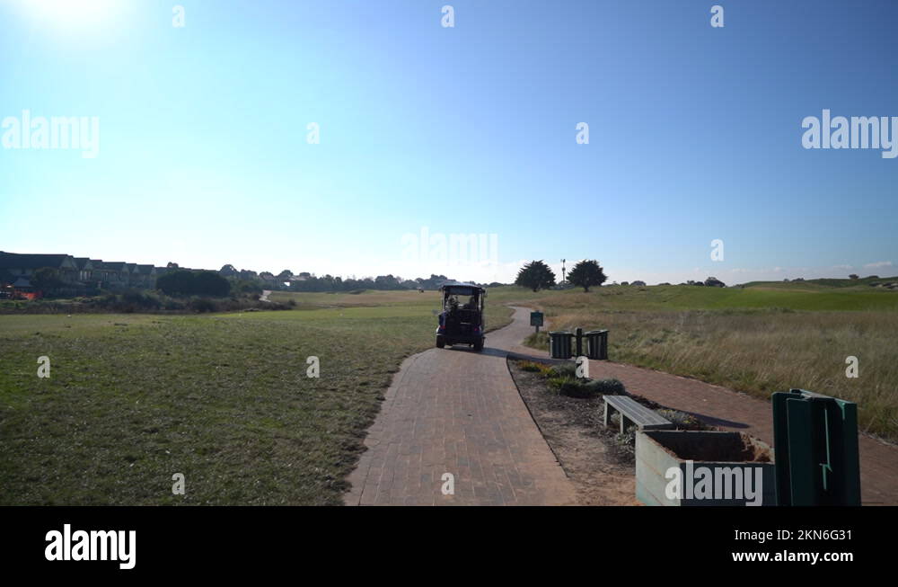 Standing golf cart with people inside in massive golf field, dolly