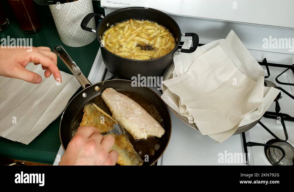 Two fillets of Walleye being cooked while French fries being deep fried