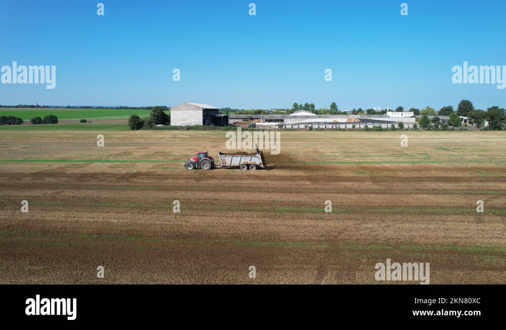 Organic fertilizer. A tractor with a trailerspreader spreads cow dung