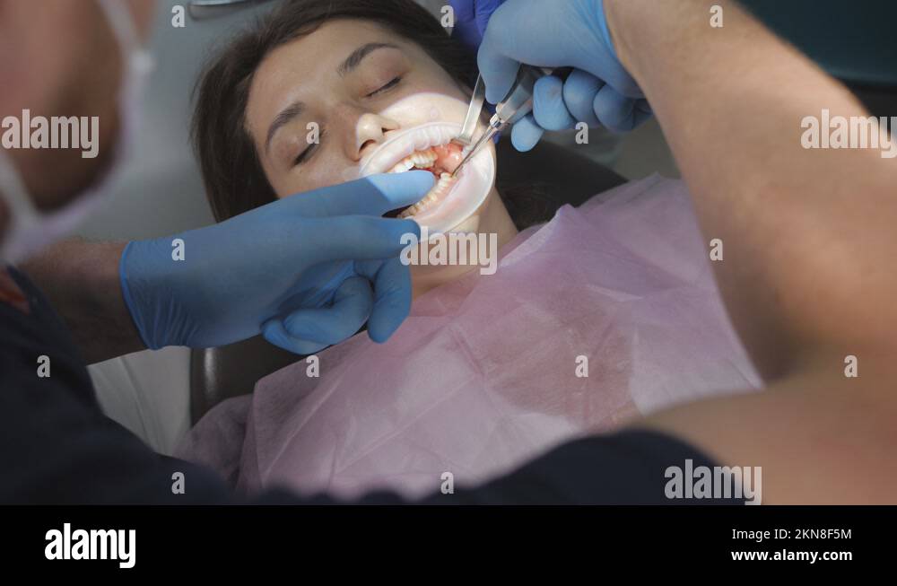 The dentist uses special tools to remove the tooth of a patient sitting