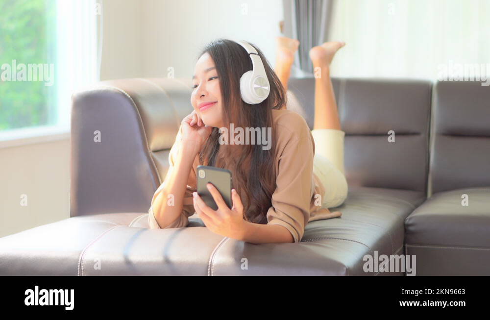A young woman playfully kicks her feet while lying on the couch as she