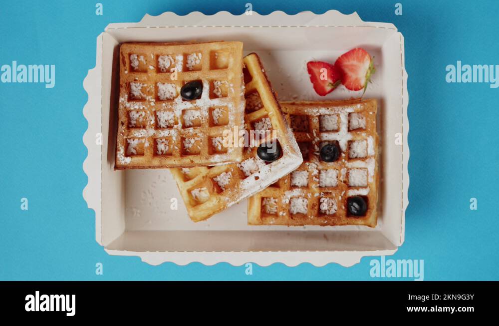 Food delivery top view. Putting blueberry on belgian waffles in lunch