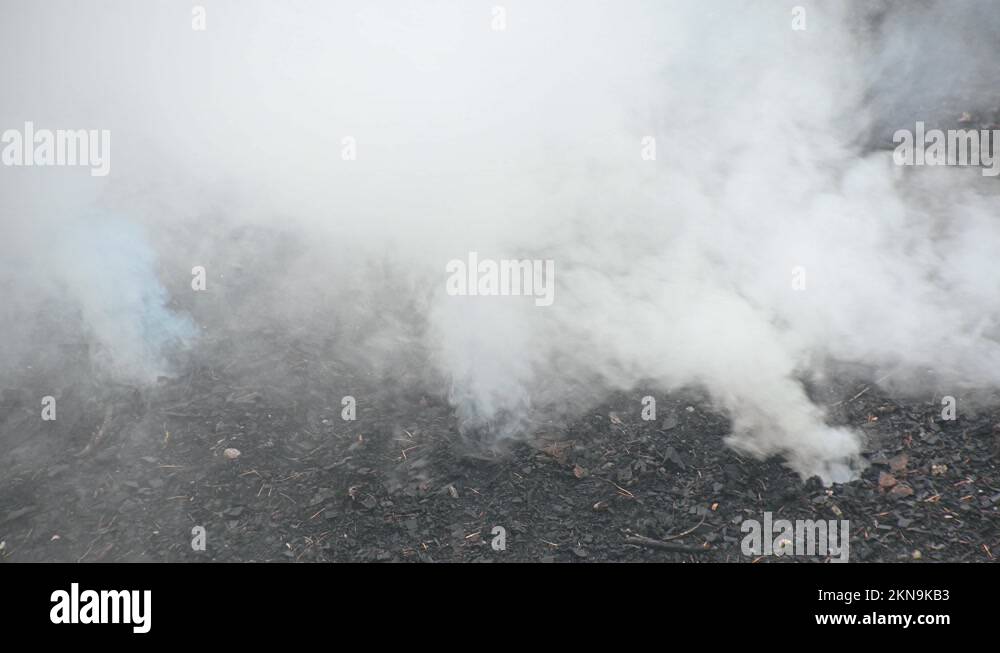Close up view of a mound of soil smoking while charcoal is being made