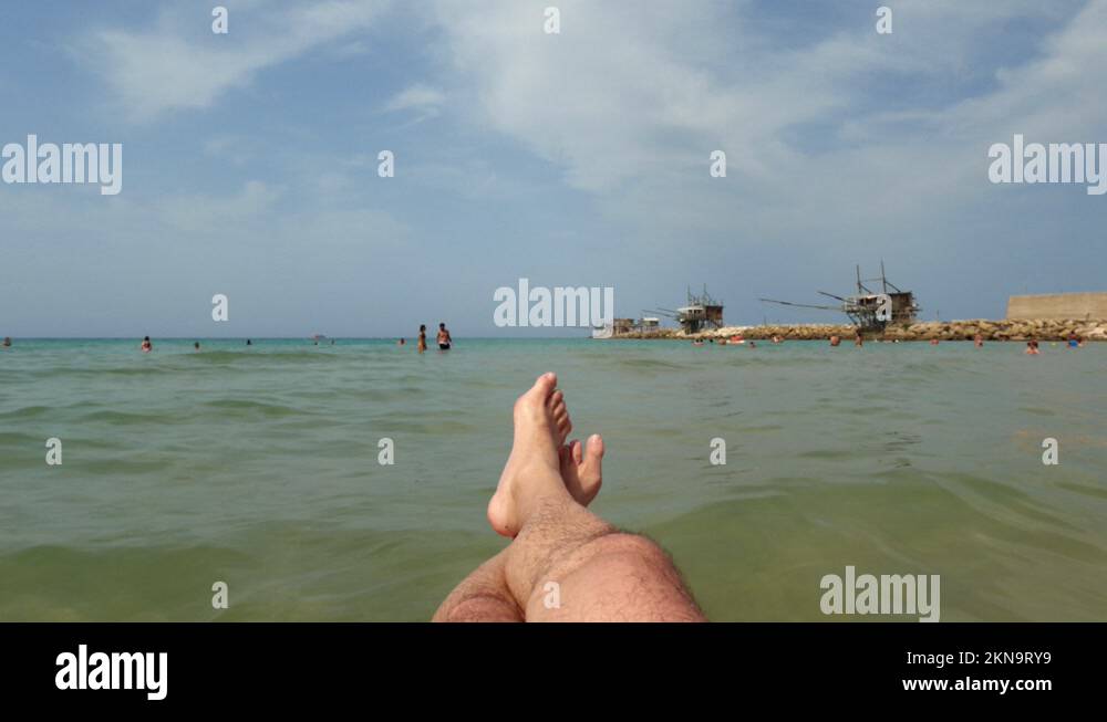 Firstperson pov of man legs relaxing and floating on inflatable