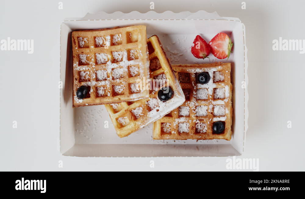 Food delivery top view. Putting blueberry on belgian waffles in lunch