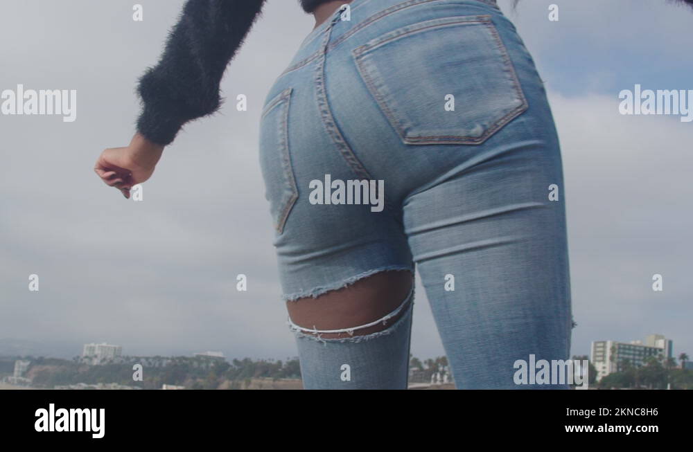 dark-skinned girl in jeans is twerking on the beach. Attractive model