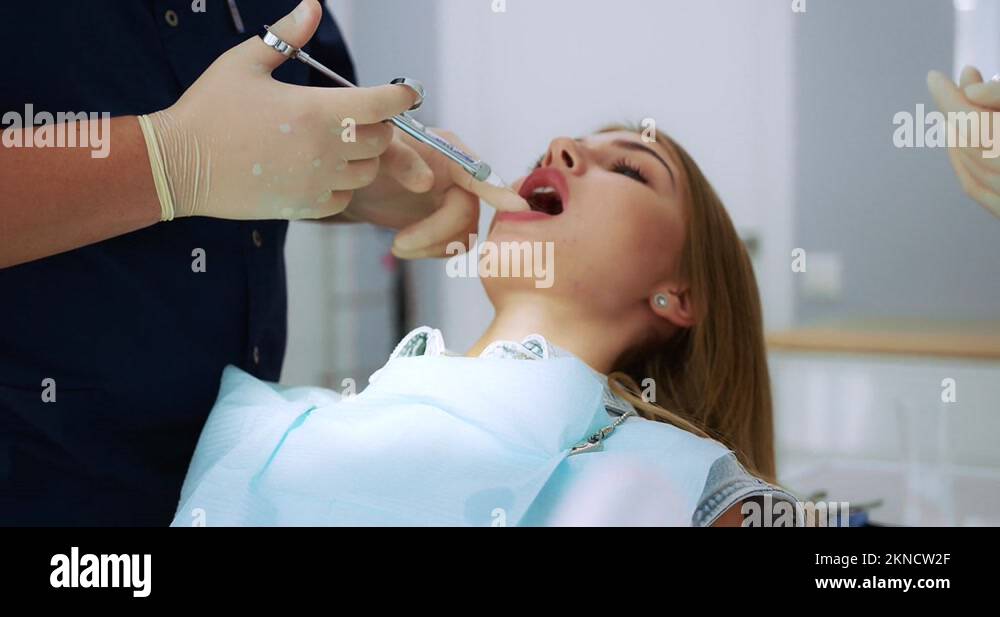 Dentist gives an analgesic injection into the tooth of a beautiful ...