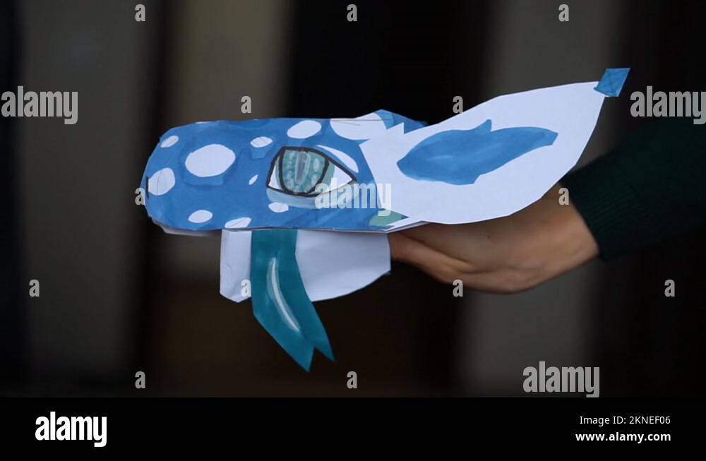 Blue origami dragon with long tongue in child hands, paper dragons