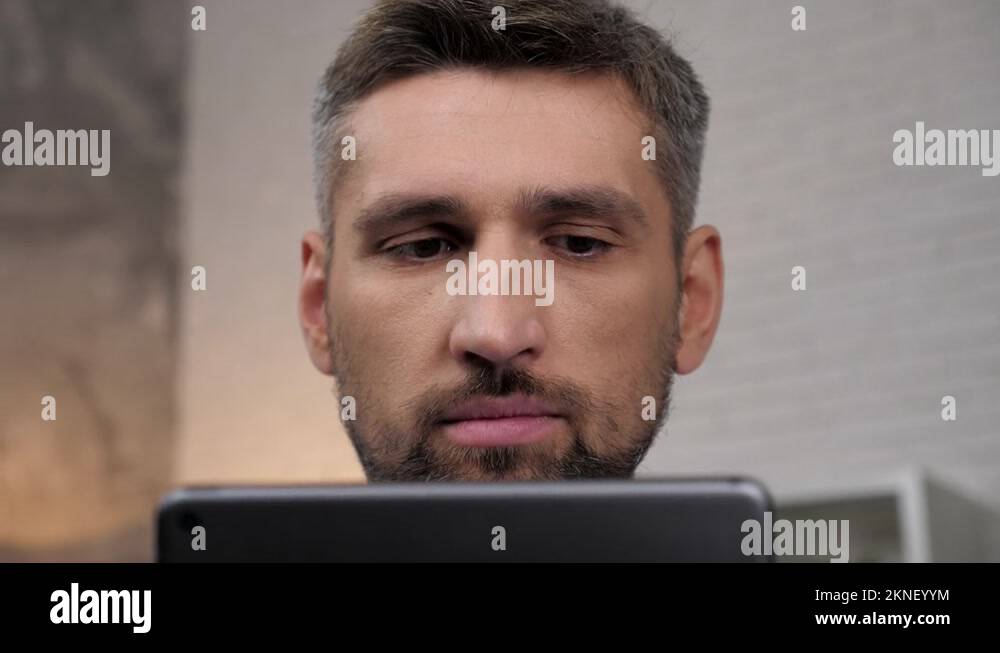 Close up face head businessman uses tablet sitting on couch at home
