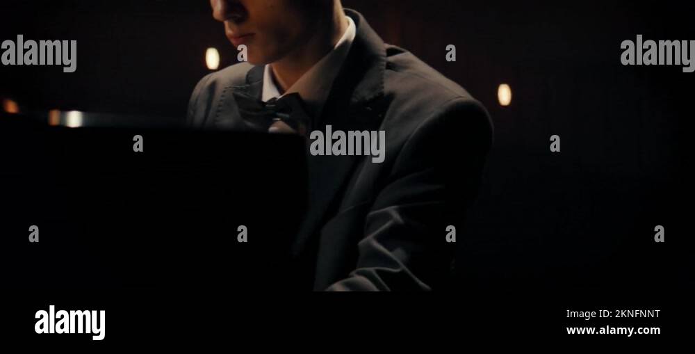 Young aspiring musician playing grand piano on a stage of a huge