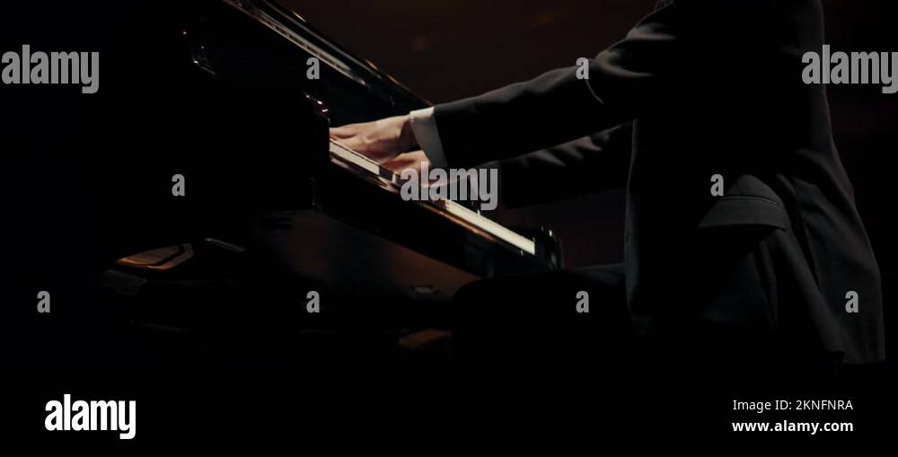 Young aspiring musician playing grand piano on a stage of a huge