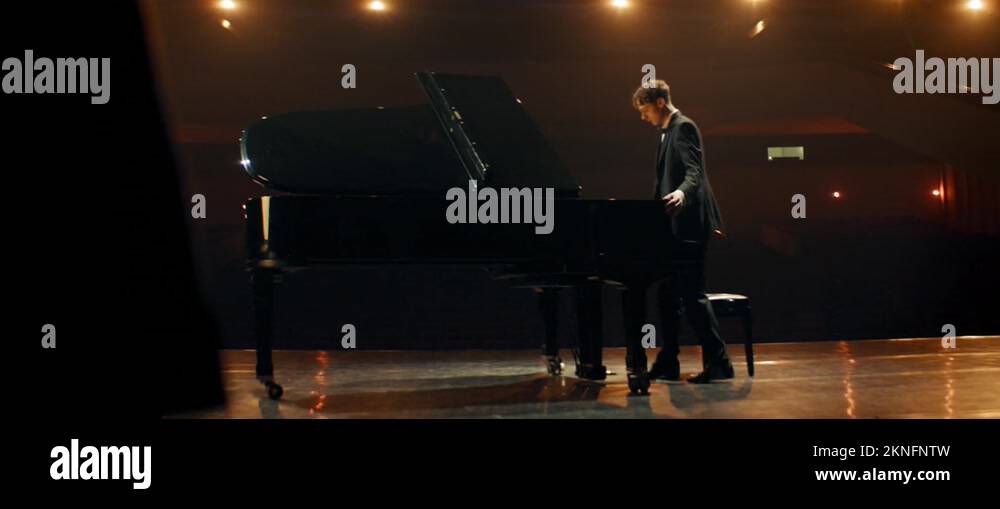 Young aspiring musician playing grand piano on a stage of a huge