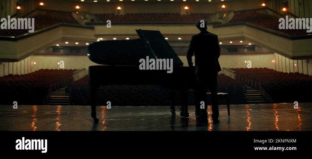 Young aspiring musician entering stage of a huge concert hall as lights