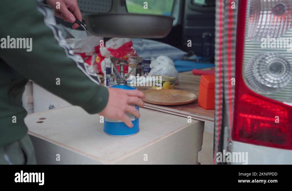 Man Cooks On A Portable Camping Stove Gas In A Campervan Near The Stock