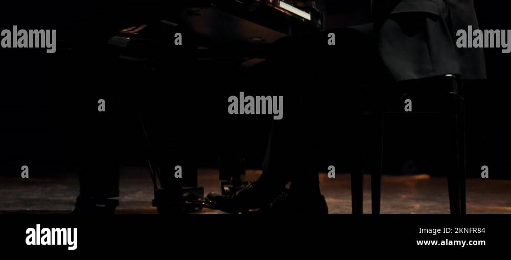 Young aspiring musician playing grand piano on a stage of a huge