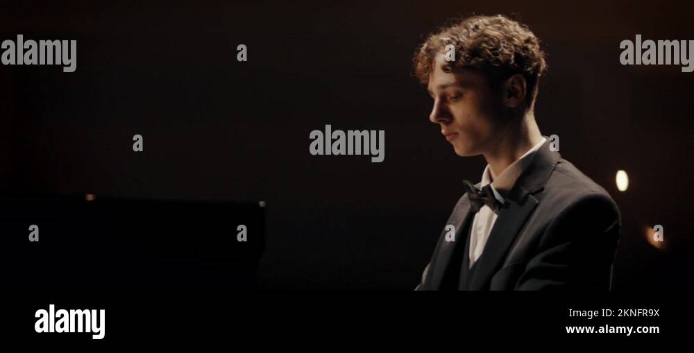 Young aspiring musician playing grand piano on a stage of a huge