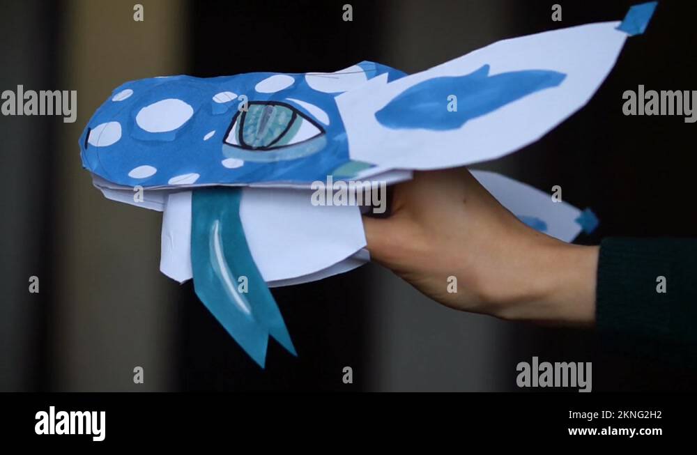 Blue origami dragon with long tongue in child hands, paper dragons