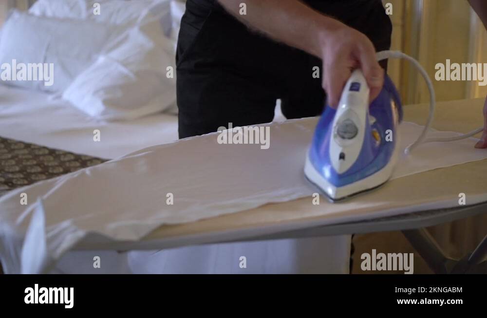 Man ironing a white shirt for a classic suit with an iron on board