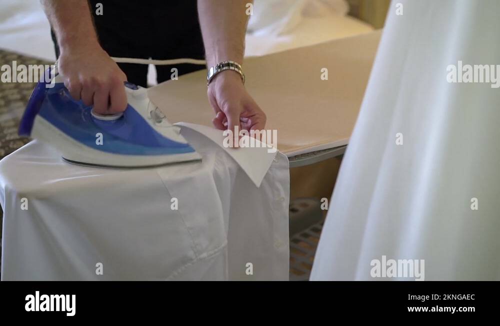 Man ironing a white shirt for a classic suit with an iron on board