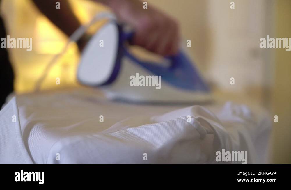 Man ironing a white shirt for a classic suit with an iron on board