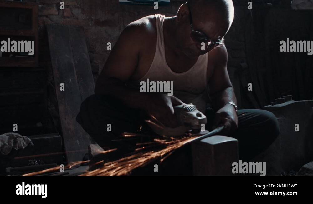 Blacksmith polishing knife blade using grinder, sparks flying Stock