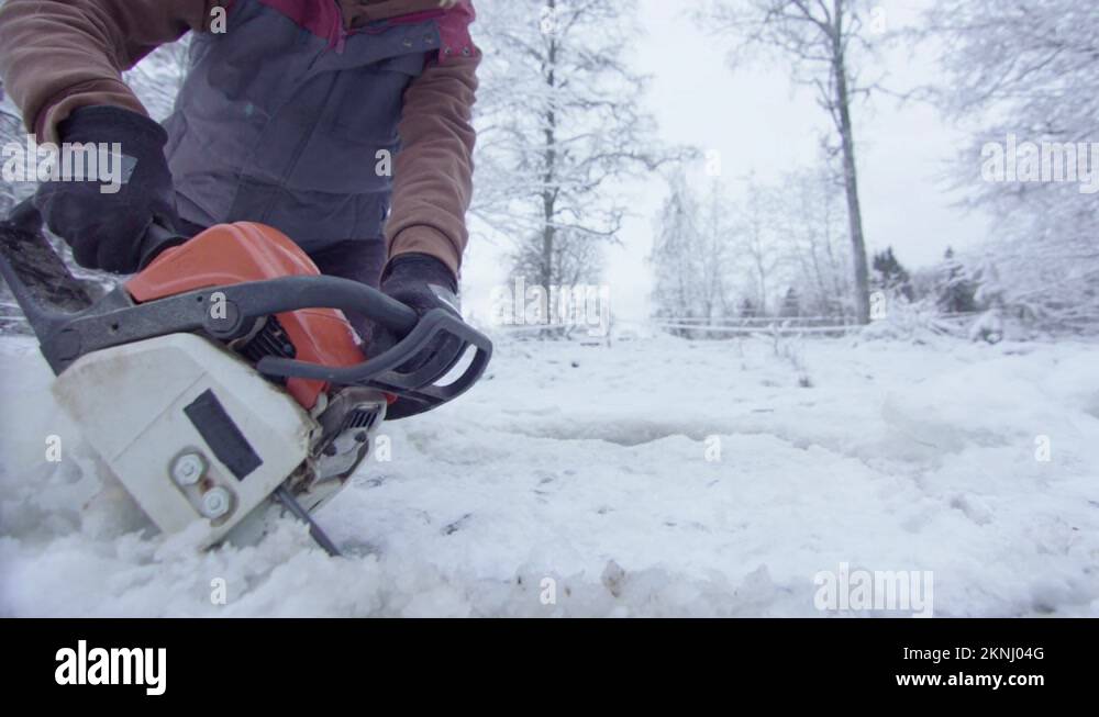 CHAINSAW CU a woman cuts an ice hole for cold water exposure therapy
