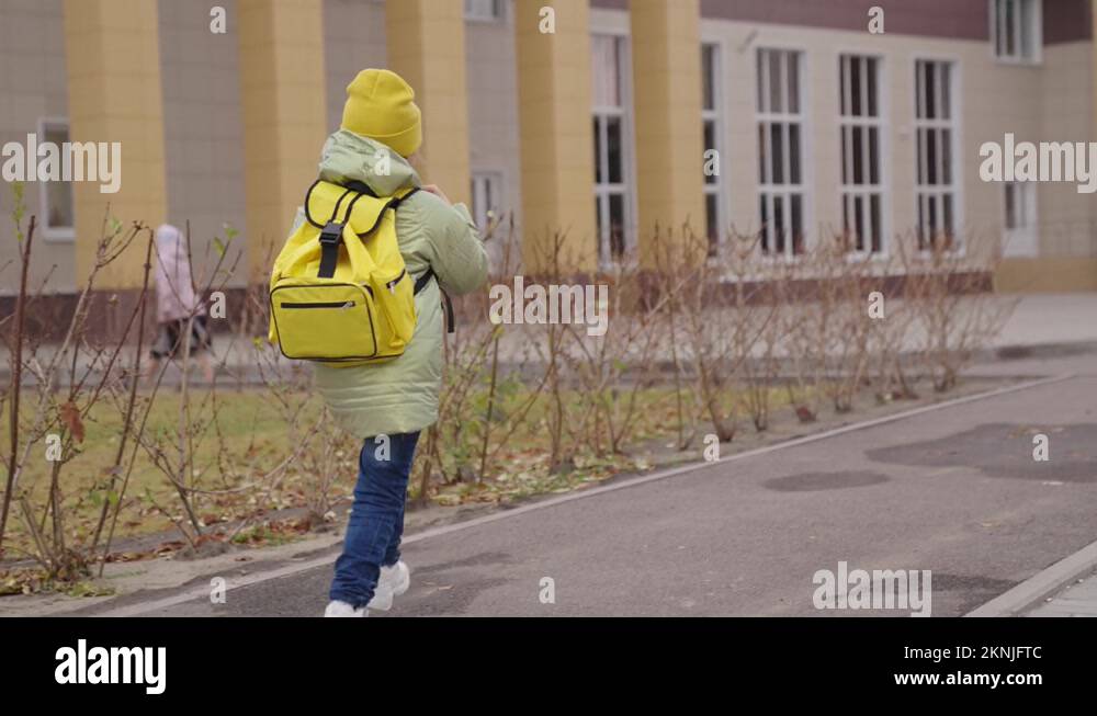 little child through schoolyard to school with a backpack, happy kid