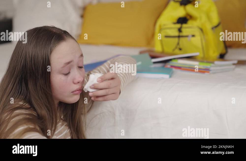 teenage girl crying wiping tears from wet eyes on her face, school