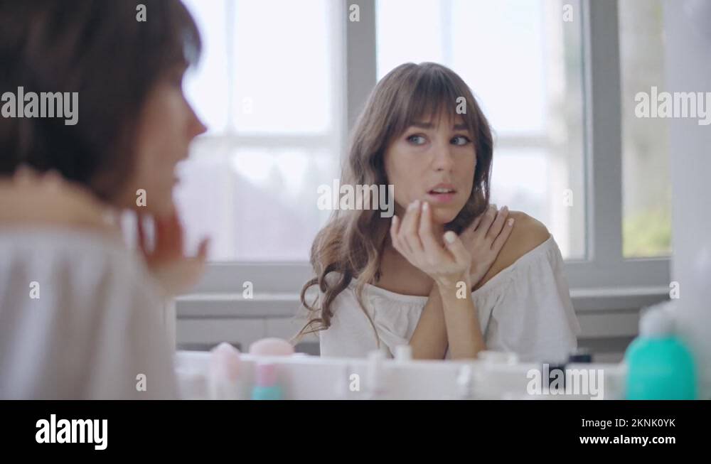 Sad young woman with vitiligo skin looking in mirror, appearance ...