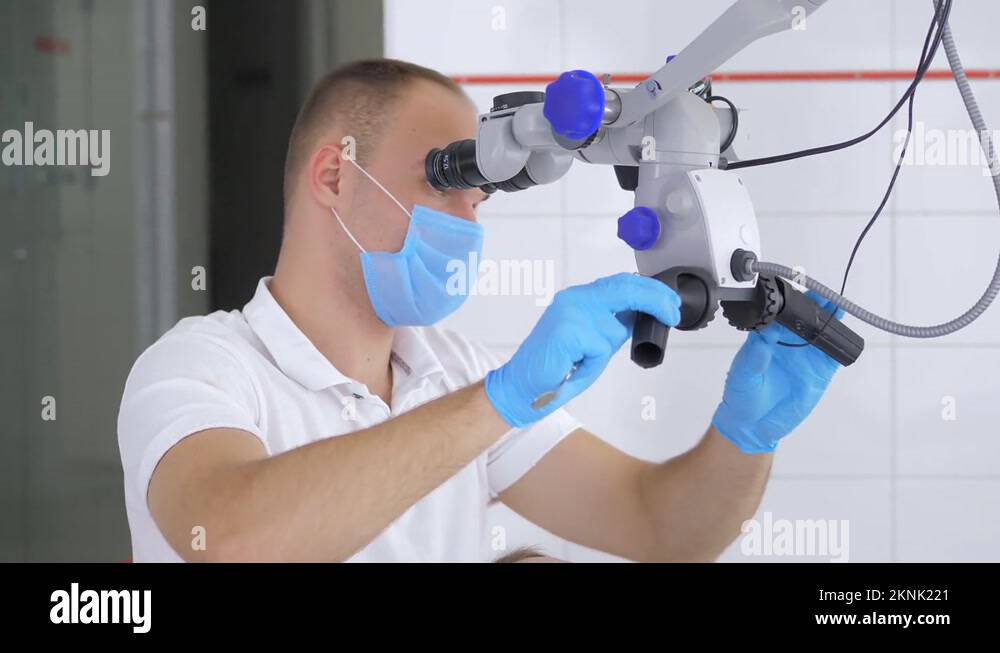 Male dentist wearing a mask and gloves using an endodontic binocular