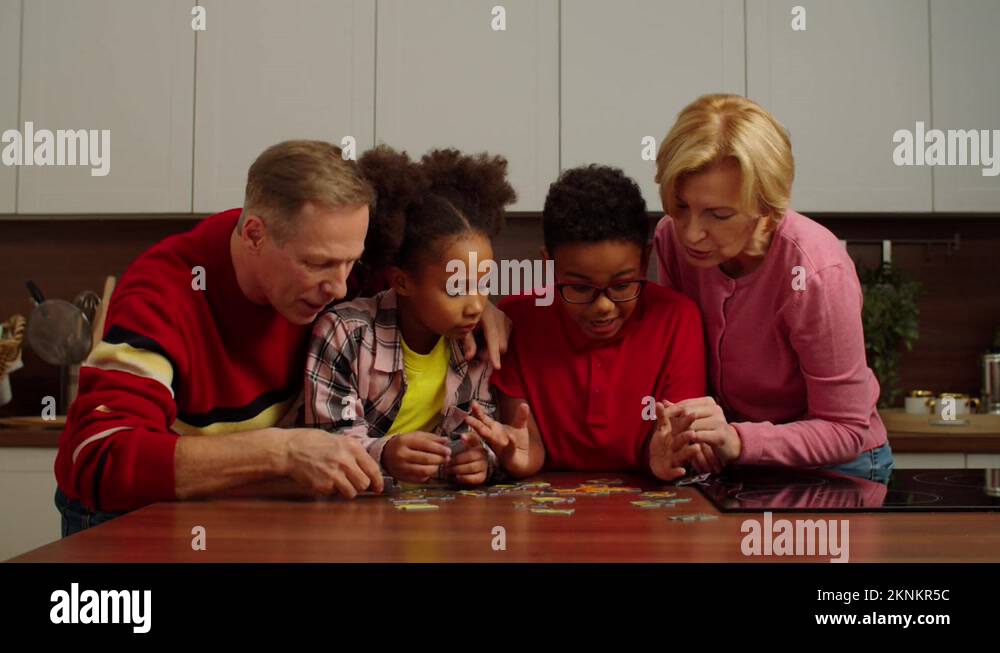 Positive grandparents with lovely multiracial children doing jigsaw ...