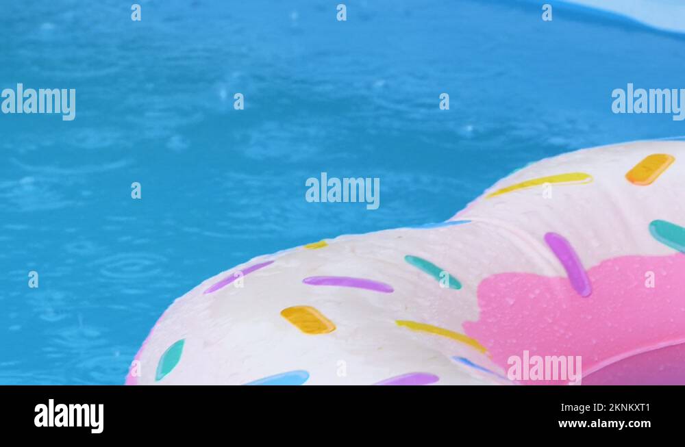 CLOSE UP Rain begins pouring down on an inflatable donut floating