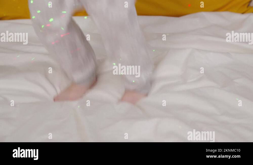 little child jumping with his feet on the bed in bedroom, happy family