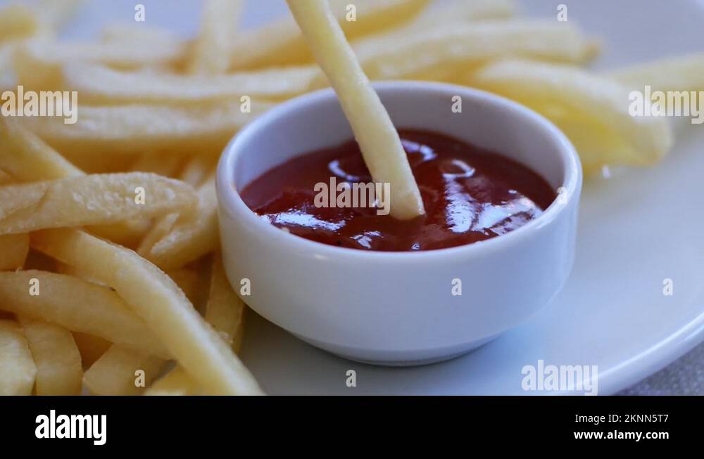 Child eats fries, dips potatoes in red ketchup sauce. Fast food is not