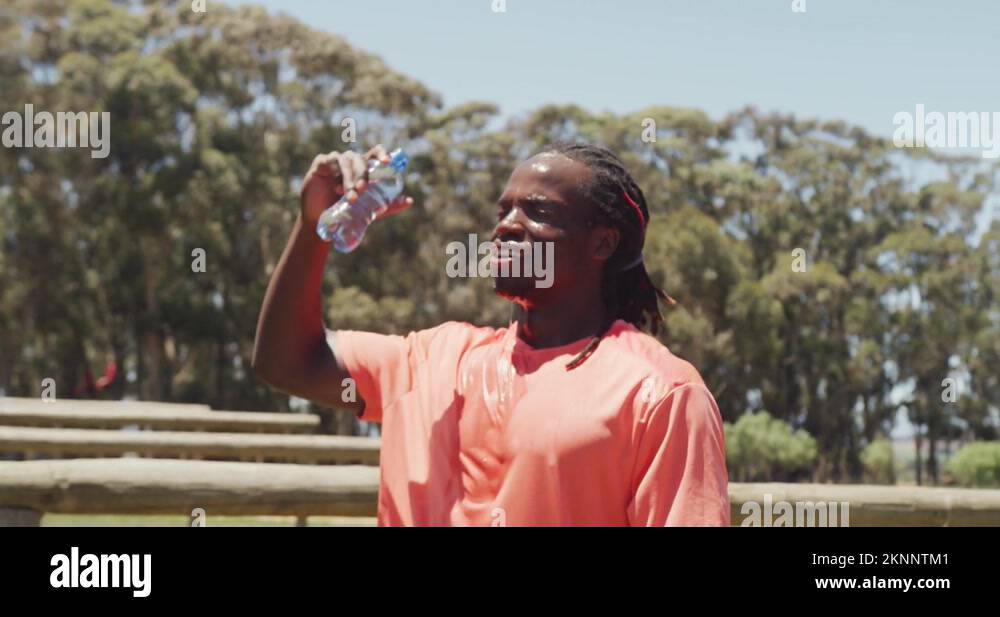 Fit african american man with dreadlocks pouring water over head after