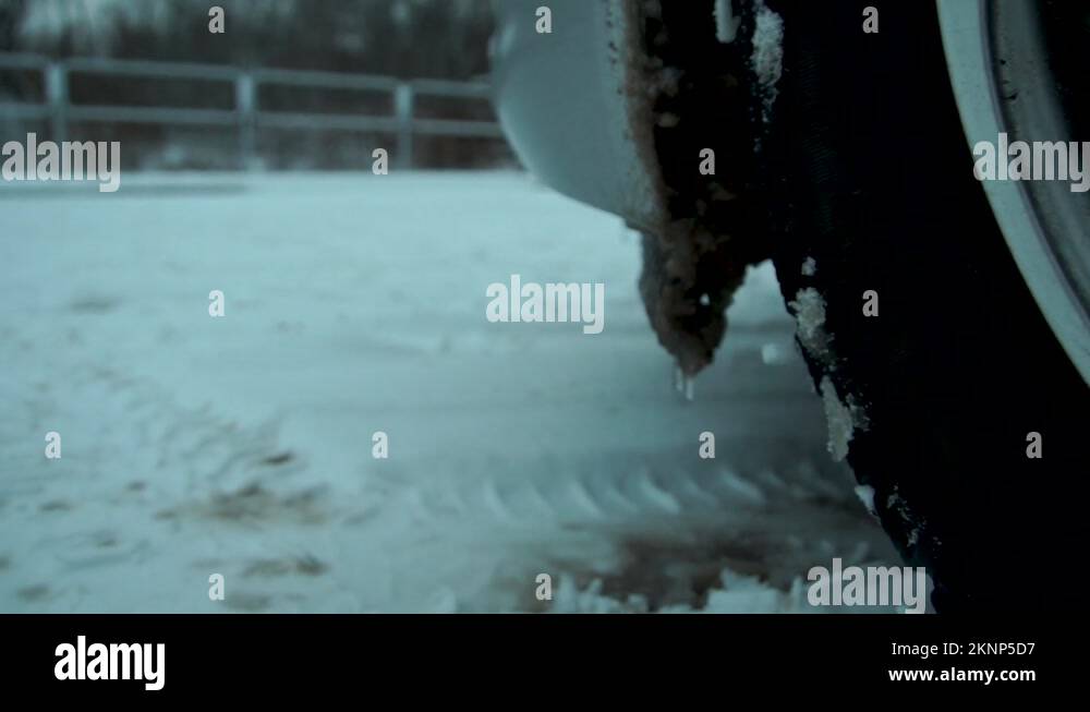 Close up shot of frozen water on the bumper and wheels of a car in