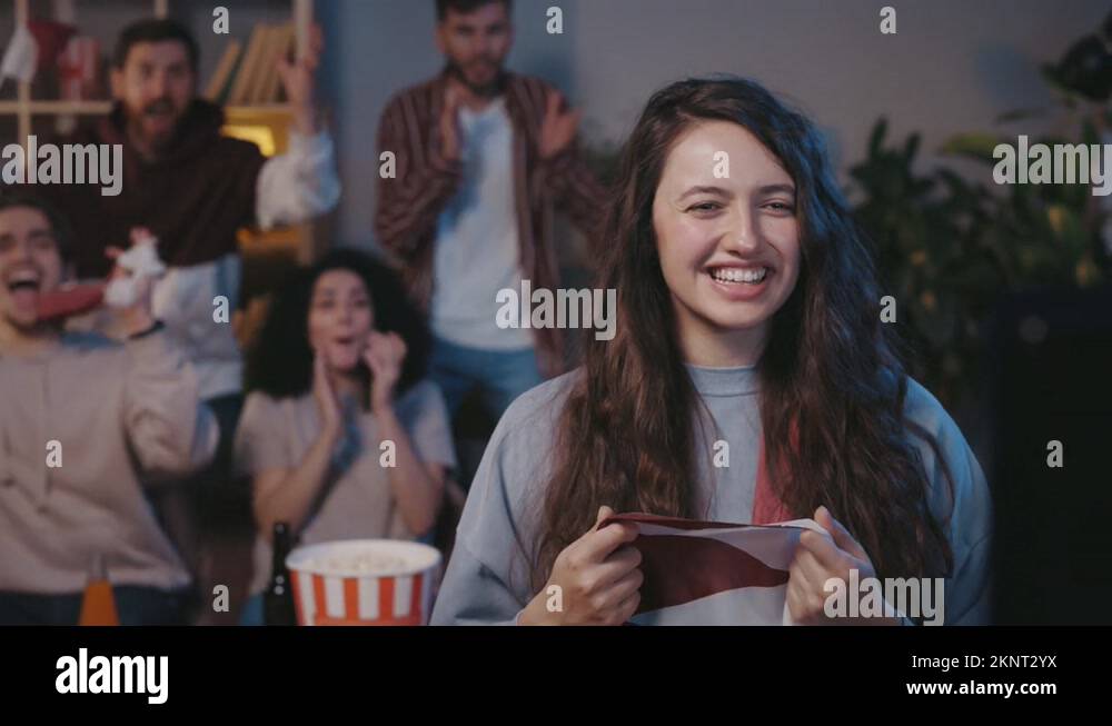 First plan of the happy excited female soccer fan sitting at home with