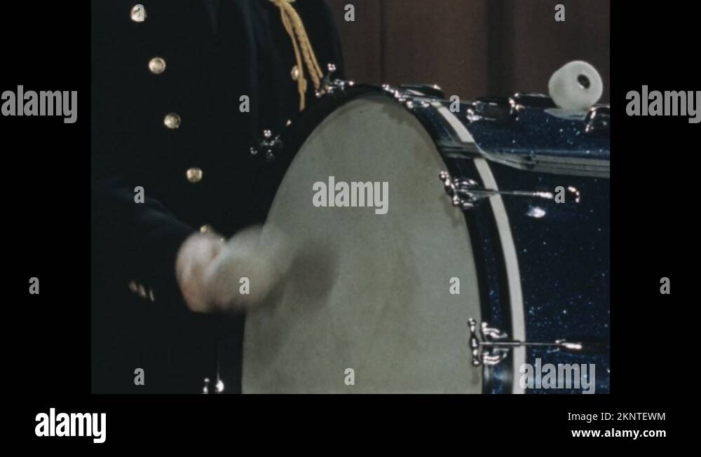 1950s Hand holding drum mallet, hitting bass drum head. Person playing