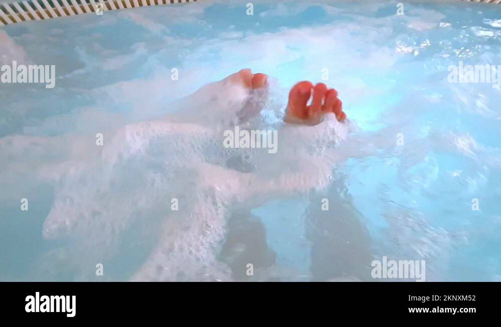 Female feet in jacuzzi spa. Legs floundering funny in blue water. Body massage Stock Video