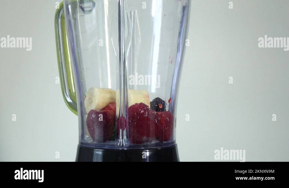 Preparation of a berrybanana milkshake with milk poured into a blender