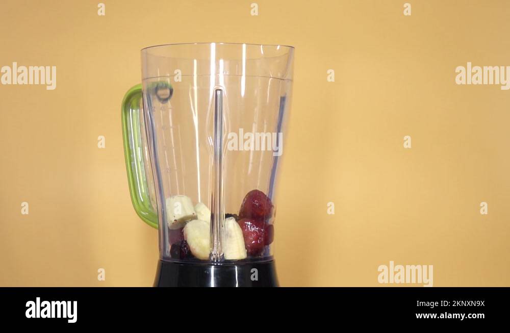 Preparation of a berrybanana milkshake with milk poured into a blender