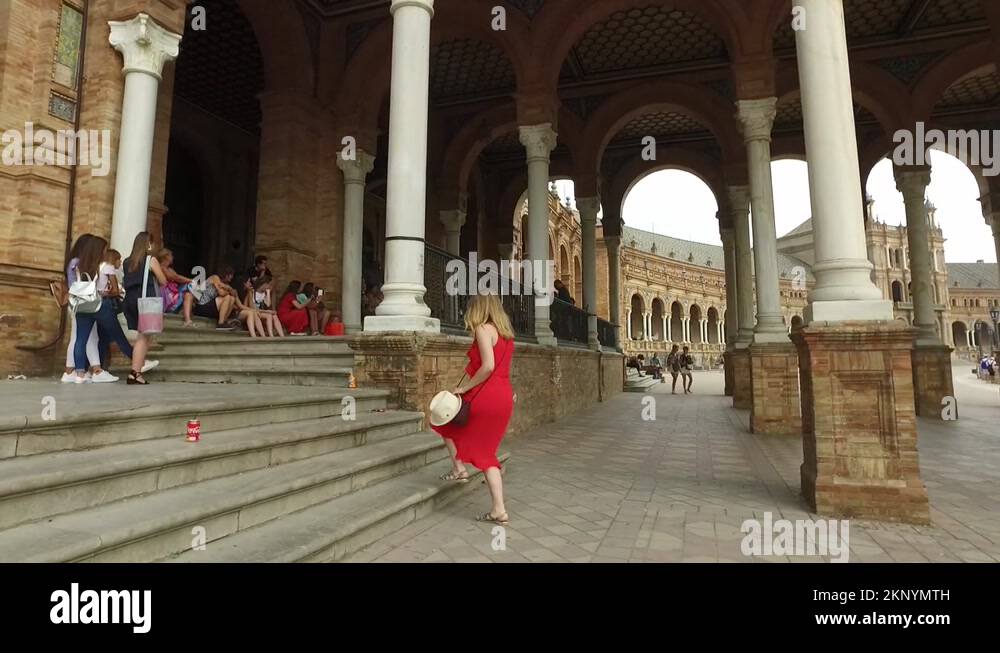 A beautiful young girl in a red dress at the square of Spain in Seville