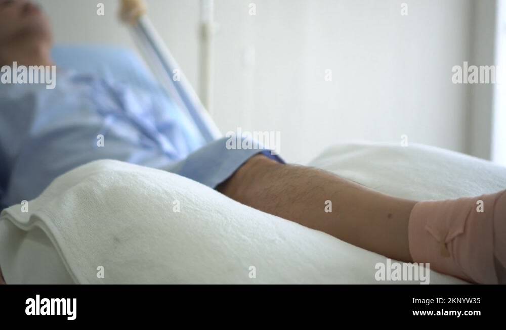 Asian man lying in hospital bed wake up and hurt from leg injury Stock