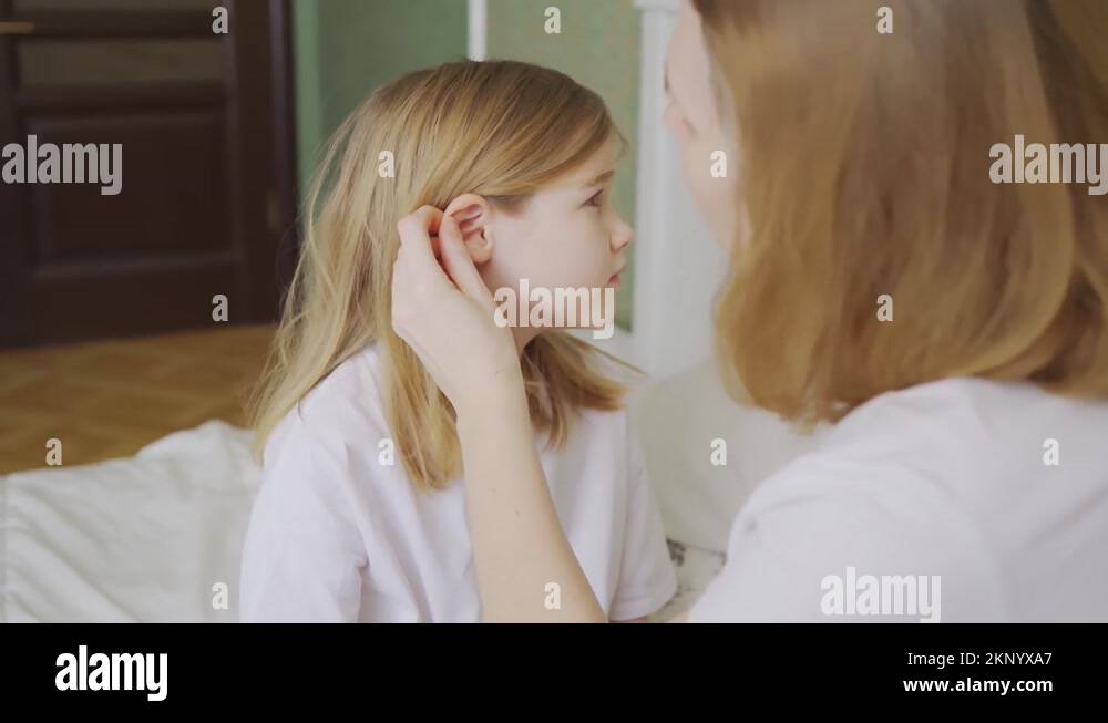 daughter complains about pain in the ear and mother examines her Stock