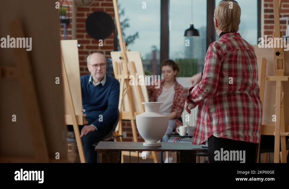 Elder artist pointing at vase on table to explain drawing technique Stock Video Footage Alamy