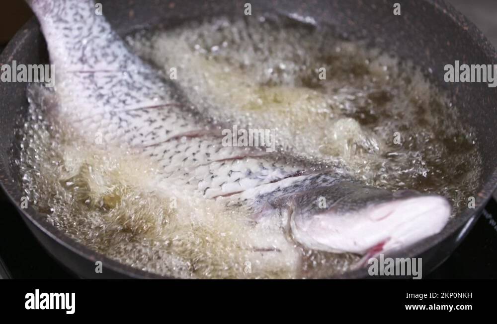 Deep Frying a Whole Fresh Fish in a Pan with Hot Oil, Fried Fish in Oil