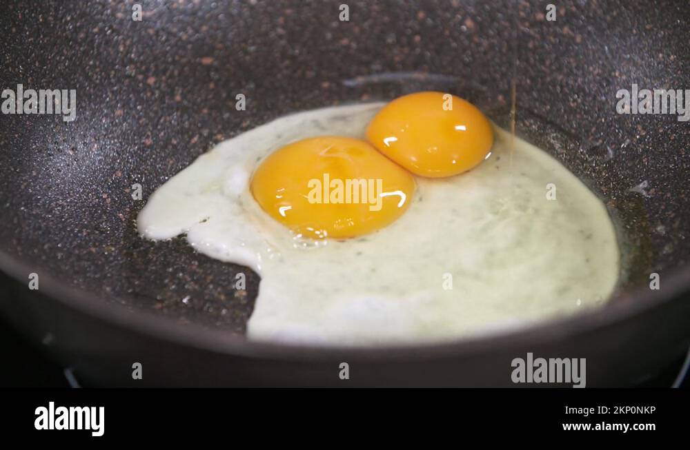 Cracking and Frying two Eggs in a Black Pan, Fried Eggs, Egg Yolk and