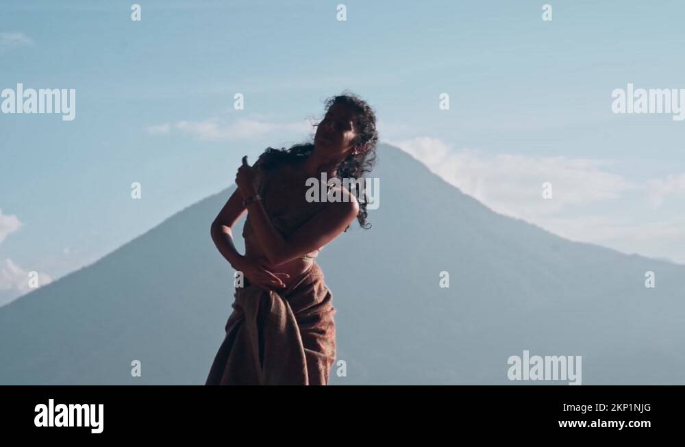 Beautiful woman dancing in front of massive volcano mount, slow motion ...