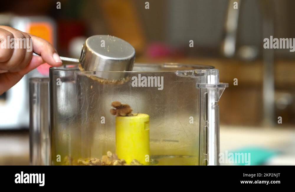 Scooping brown sugar into a food processor to mix with walnuts to make a Stock Video Footage Alamy