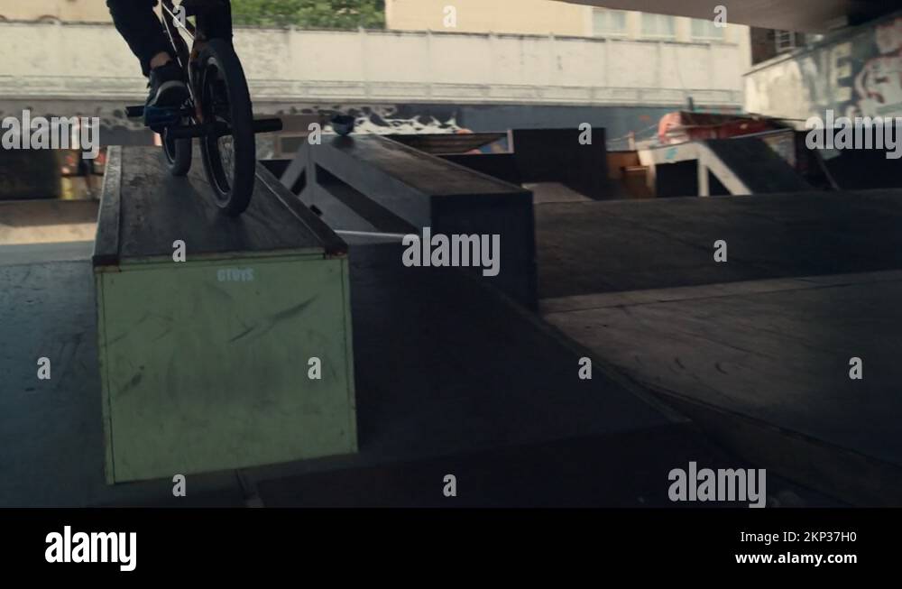 Active bmx rider training skills at skatepark. Biker racing up in ramp